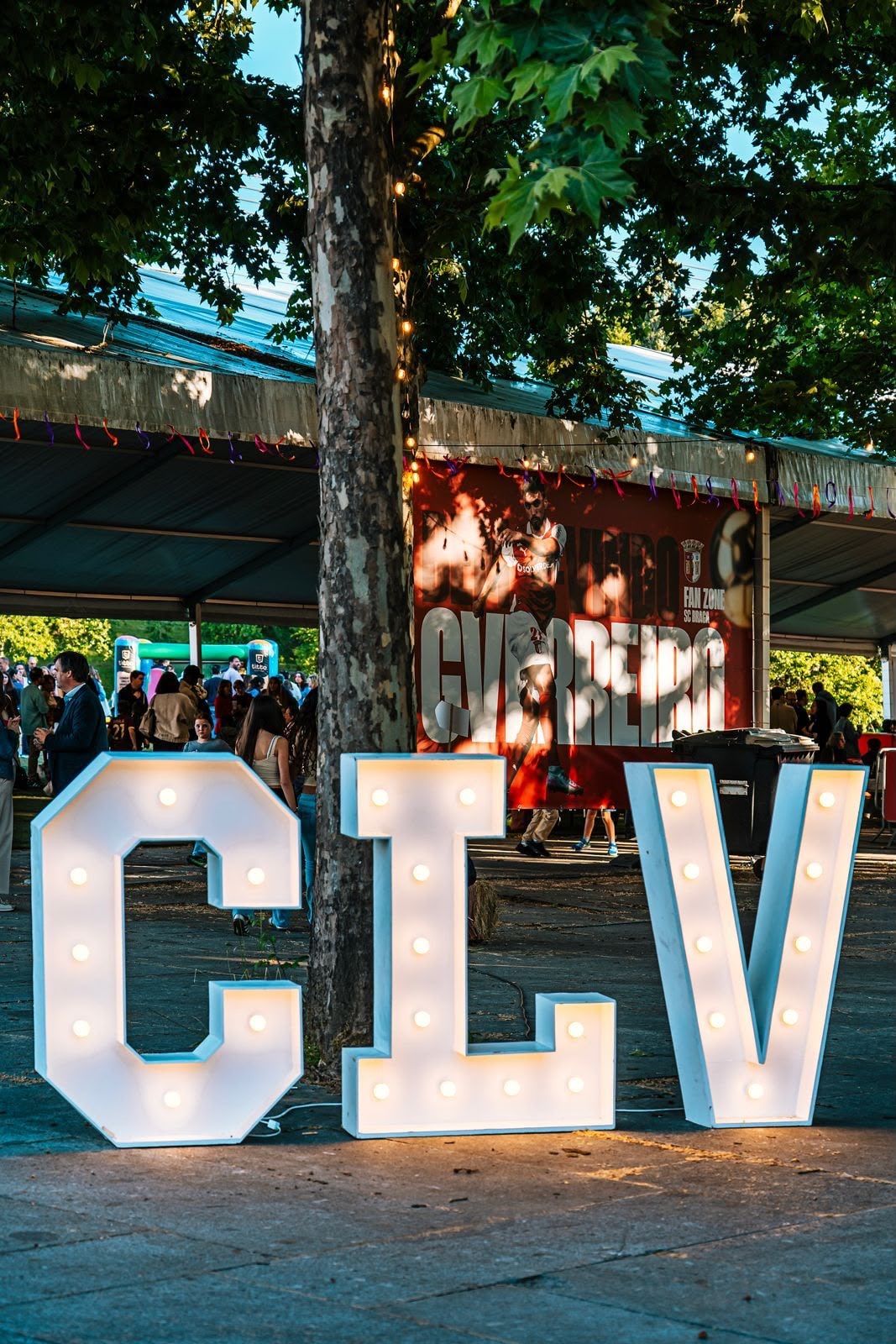 Letras gigantes CLV iluminadas numa festa do colégio ao fim da tarde